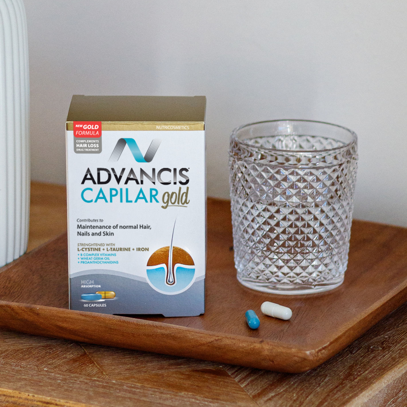 Advancis Capilar gold supplement box with a glass and capsules on a wooden tray | health boutique